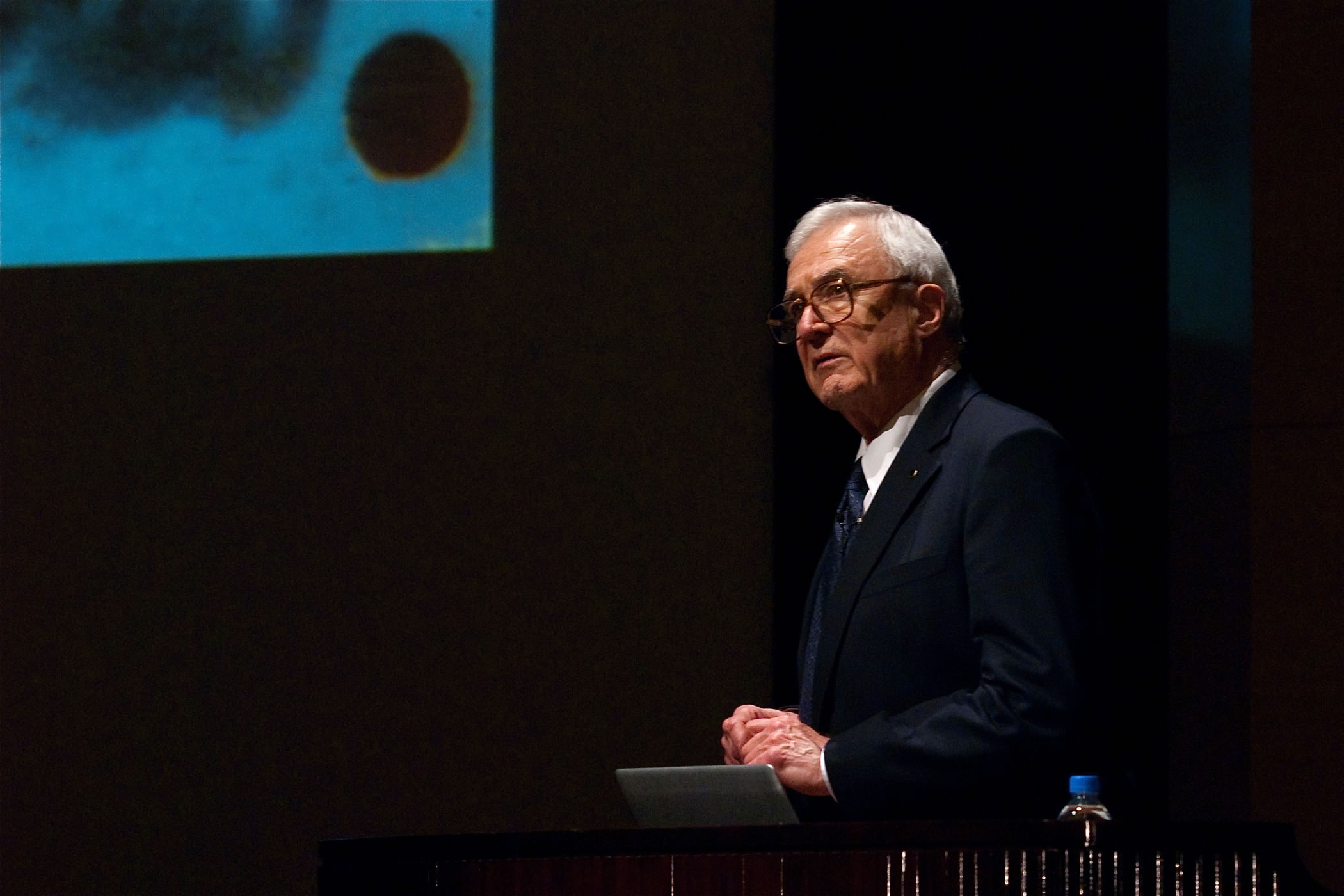 Dr. David E. Kuhl speaking at a lectern during a scientific presentation